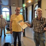 Übergabe der Urkunde durch Rudolf Gröger (rechts) an Markus Leucht (im gelben Shirt)